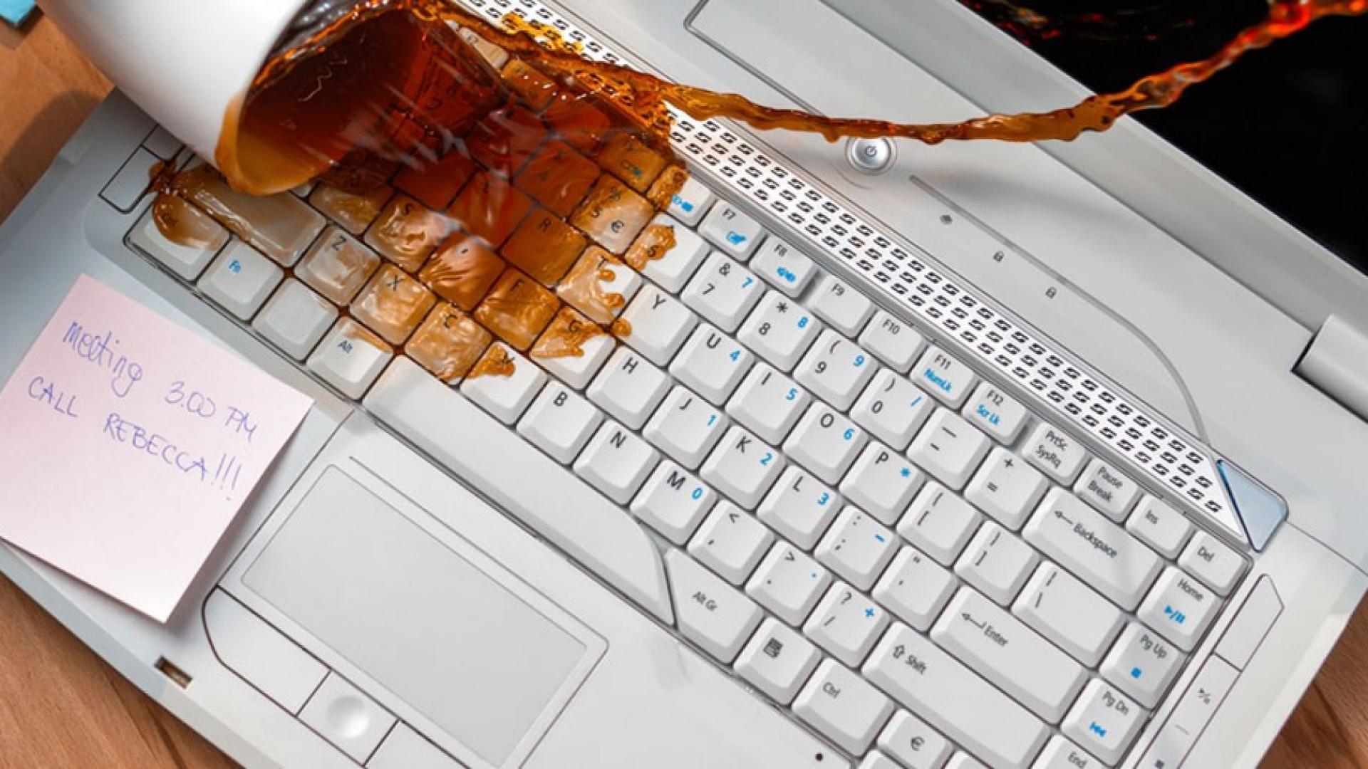 Ein voller Kaffebecher stürzt auf eine Laptoptastatur