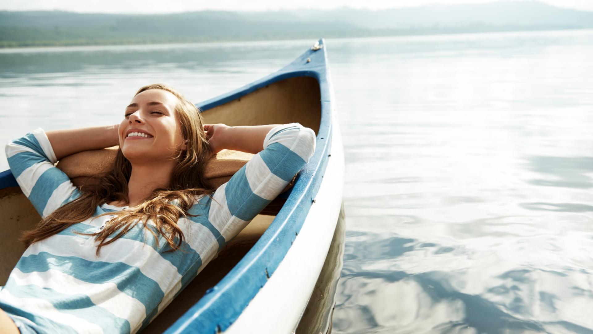 Eine junge Frau liegt entspannt in einem kleinen Boot.